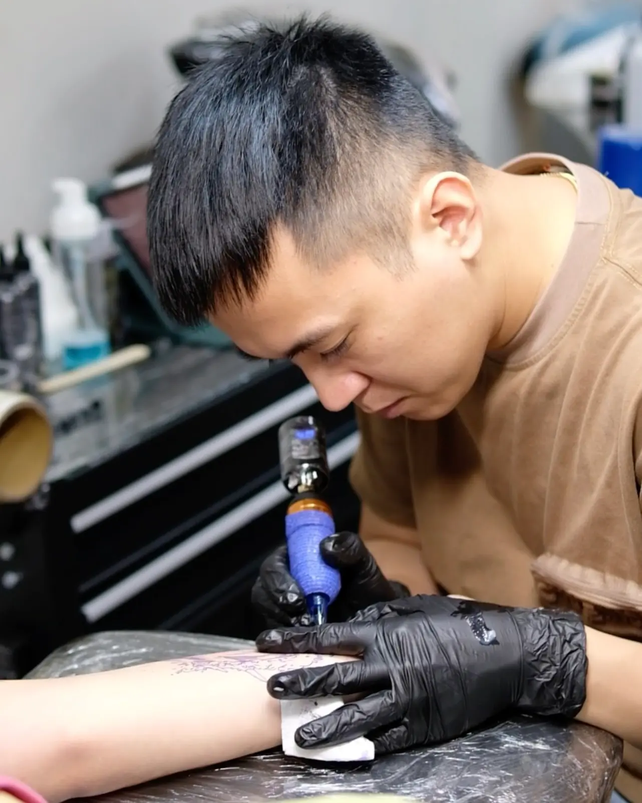 A professional tattoo artist at H2M Tattoo Studio in Hanoi working on a custom design