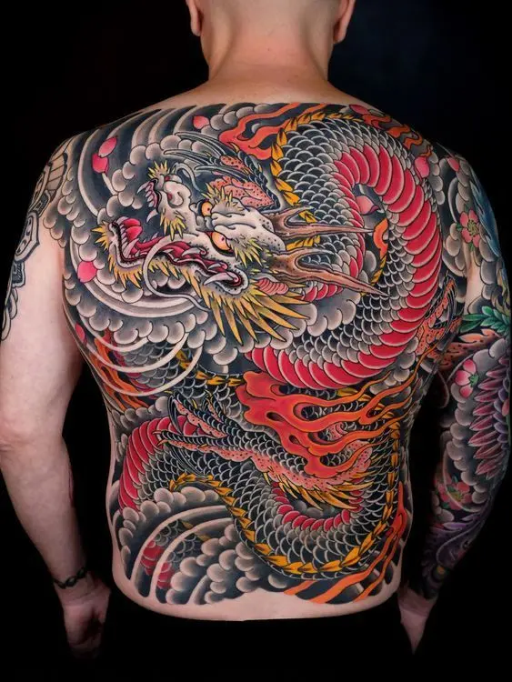 Full-back Japanese dragon tattoo with bold lines, wave patterns, and traditional color palette representing strength and spiritual protection