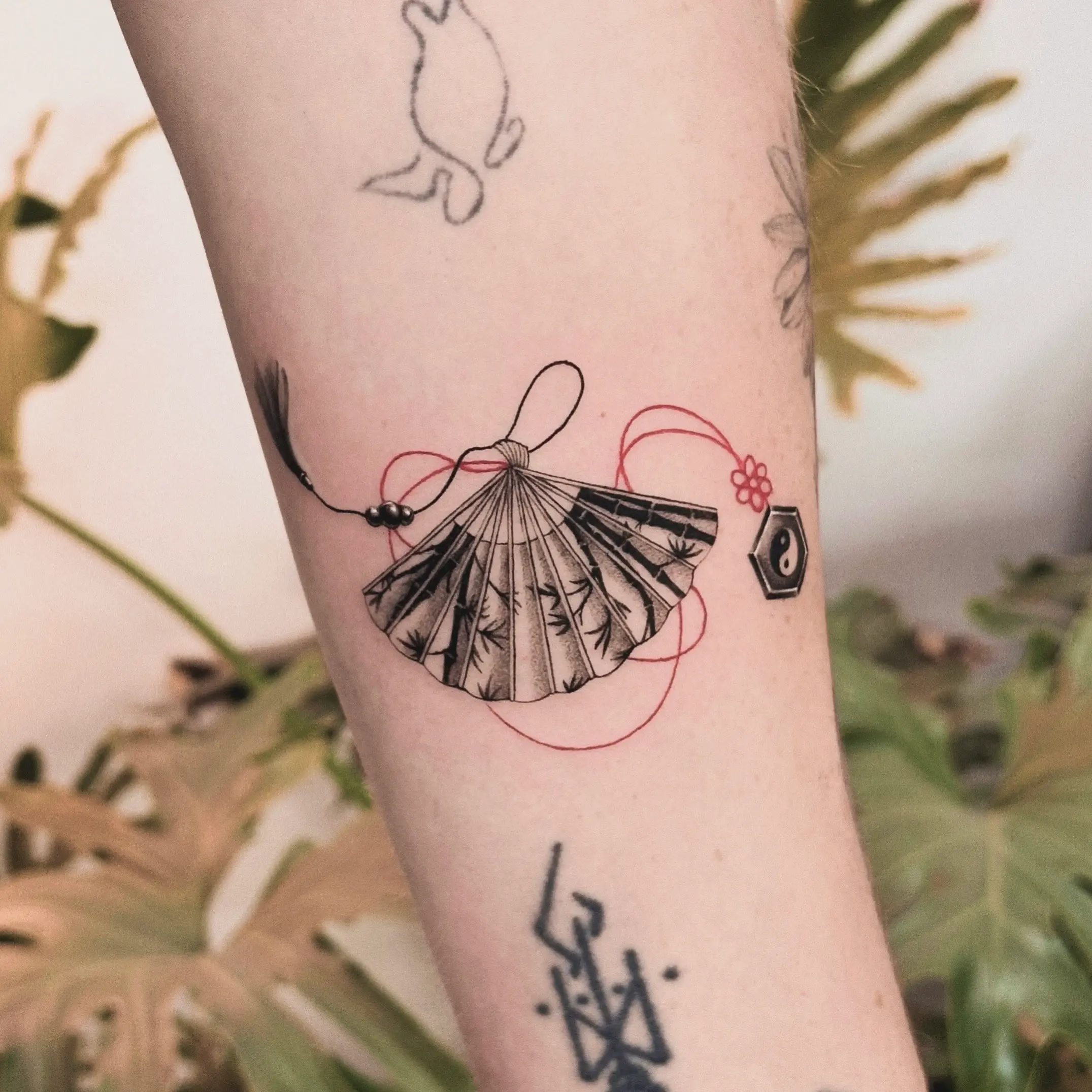A modern fusion Vietnamese tattoo of a traditional fan with bamboo detail, blending cultural elements with contemporary tattoo style